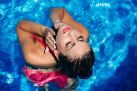 Fashion photosession of a sexy girl with make up in a pink swimsuit. View from aboveの写真素材