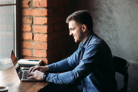 Man with a beard uses a laptop in a cafeの写真素材