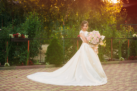 Young girl in wedding dress in park posing for photographerの写真素材