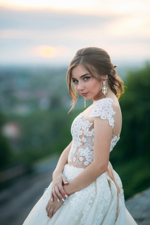 Teenage girl in wedding dress on city. Background town sunsetの写真素材