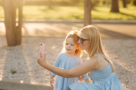 Mom and her little daughter make selfie in the parkの写真素材