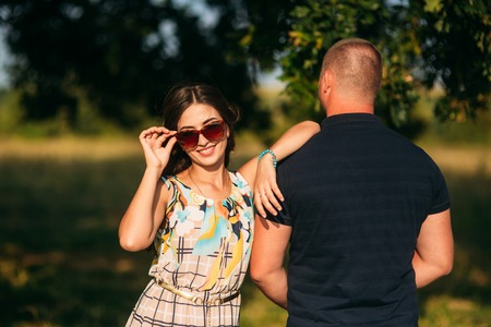 A beautiful couple is resting outside the city, sitting near a big tree in the garden. Love storyの写真素材