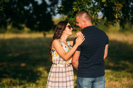 A beautiful couple is resting outside the city, sitting near a big tree in the garden. Love storyの写真素材