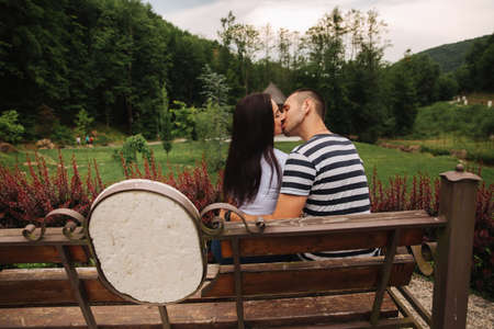 A guy and a girl enjoy each other in a romantic atmosphere and sits on the benchの写真素材