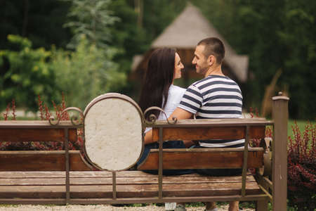 A guy and a girl enjoy each other in a romantic atmosphere and sits on the benchの写真素材