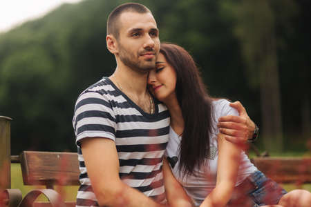 A guy and a girl enjoy each other in a romantic atmosphere and sits on the benchの写真素材