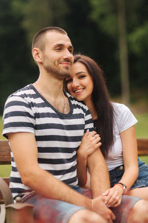 A guy and a girl enjoy each other in a romantic atmosphere and sits on the benchの写真素材