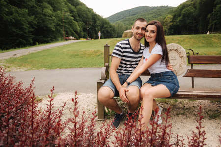 A guy and a girl enjoy each other in a romantic atmosphere and sits on the benchの写真素材
