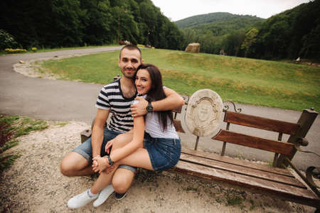 A guy and a girl enjoy each other in a romantic atmosphere and sits on the benchの写真素材
