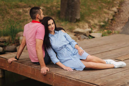 A guy and a girl enjoy each other in a romantic atmosphere, sits on the pierの写真素材