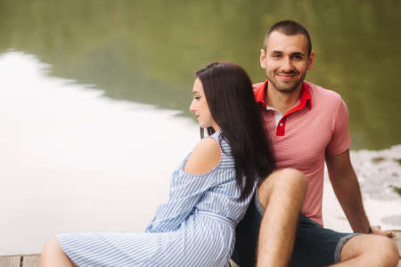 A guy and a girl enjoy each other in a romantic atmosphere, sits on the pierの写真素材