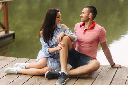 A guy and a girl enjoy each other in a romantic atmosphere, sits on the pierの写真素材