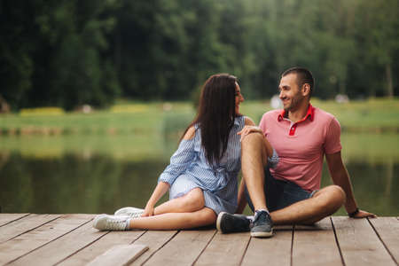 A guy and a girl enjoy each other in a romantic atmosphere, sits on the pierの写真素材