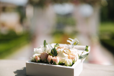 Wedding rings in little floral box. Beautiful beckground of wedding arch.