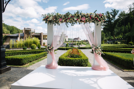 Weddind decoration on open air. Floral decor of a beautiful white arch. Beautiful beckground view of trees.の写真素材