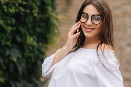 Happy young lady talking on mobile phone on the streetの写真素材