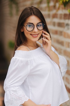 Happy young lady talking on mobile phone on the streetの写真素材