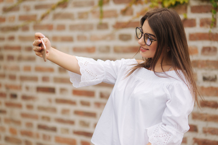 Beautiful girl make a selfie on smart phone outsideの写真素材