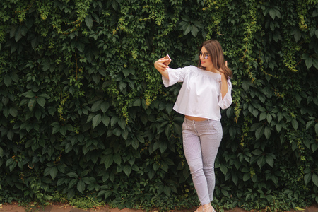Beautiful girl make a selfie on smart phone outsideの写真素材