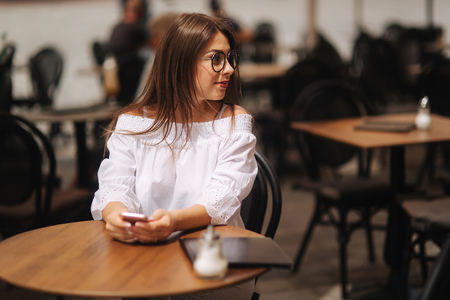 Business girl sitting in cafe and texting on the smart phone. she wearing a white shirt and sunglasessの写真素材