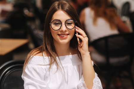 Portrait of outgoing lady telling by phone and waiting waiter. She looking at the street. Business and rest conceptの写真素材