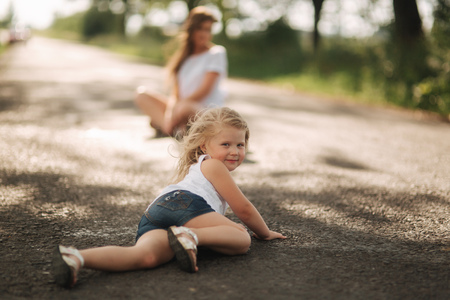 little girl playing with mom in the park in summer day during the sunsetの写真素材