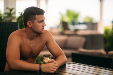 Young man sitting of the beach club bar and drinking tonicの写真素材