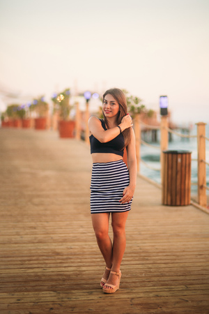 Attractive girl walking on pier near the sea in sunset timeの写真素材