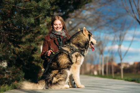 A smiling girl is walking with a dog along the embankment. Beautiful husky dog