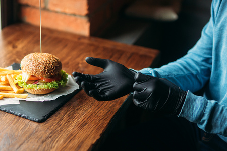 Man in black gloves takes a burger in his handsの写真素材