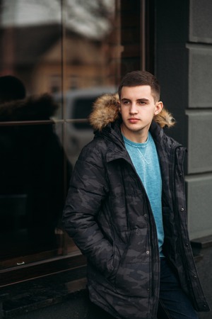 Man in a gray jacket is standing on the street and posing for a photographerの写真素材