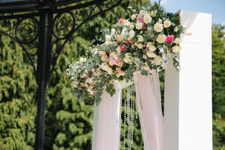 Weddind decoration on open air. Floral decor of a beautiful white arch. Beautiful beckground view of treesの写真素材