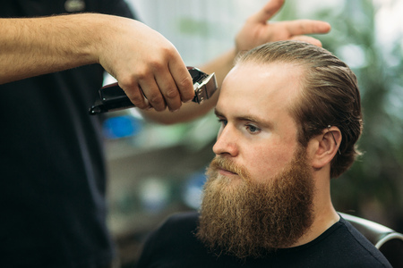 Handsome man Getting Haircut By Barber While Sitting In Chair At Barbershopの写真素材