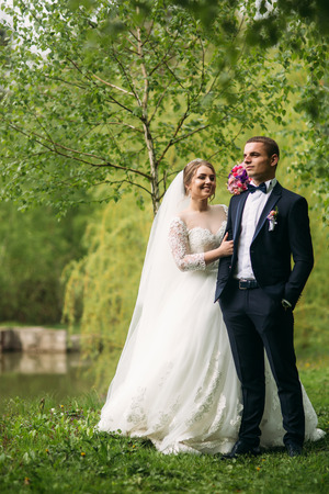 The newlyweds are walking in the park on the wedding day. The bride and groom Enjoying at the wedding dayの写真素材