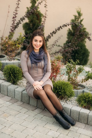 Lady sits on the curb and poses to photographer. Autumn photosessionの写真素材