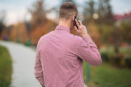 Stylish guy in a chekered shirt using a phoneの写真素材