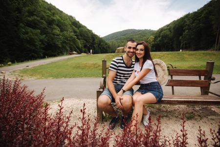A guy and a girl enjoy each other in a romantic atmosphere and sits on the benchの写真素材