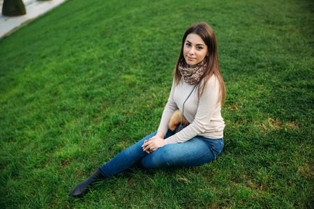 Attractive young lady sist on grass. Background of eiffel towerの写真素材