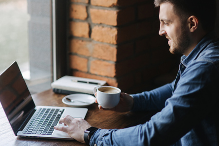 Man with a beard uses a laptop in a cafeの写真素材