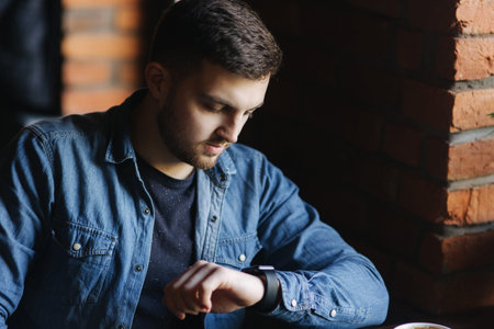 Young businessman look at the watchl in cafe while he use a laptopの写真素材