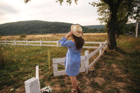 Back view of pregnant woman in hat. Background of mountainsの写真素材