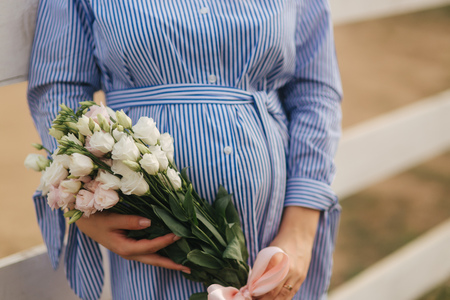 Charming pregnant woman hold a bouquet of flowers. Happy woman smile. Future mother in natureの写真素材