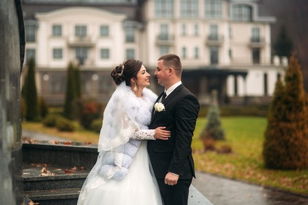 Groom and bride walking in the park on their wedding day. Autumn weather. Rair. Couple umbrellaの写真素材