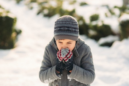 A boy warms his hands from the cold in winterの写真素材