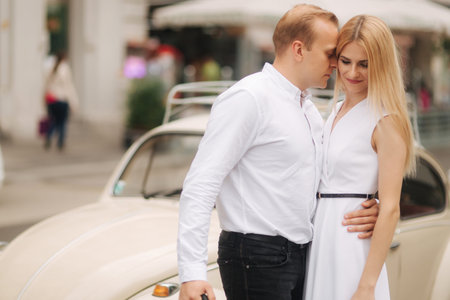 Man and woman stand near their car with umbrella. Beautiful couple in the city. Black umbrella....