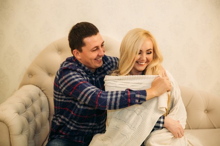 Happy couple in holiday spirit showing affection for one another. Dressed in plaid clothes. Gentle pregnant womanの写真素材