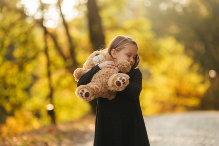 Portrait of little girl which hold teddy bear in hands. Happy child in the park. Beautiful girl model smile to cameraの写真素材