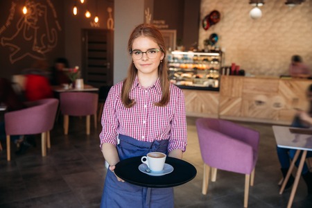 Waitress offering a cup of coffee in cafe. cappuchinoの写真素材
