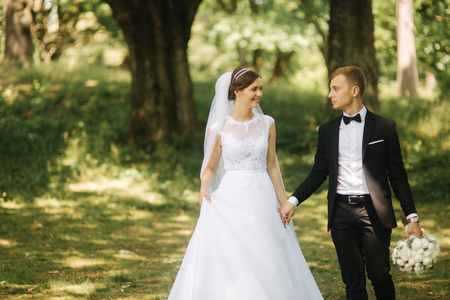 Happy couple walk in the park in their wedding day. Groom and brideの写真素材