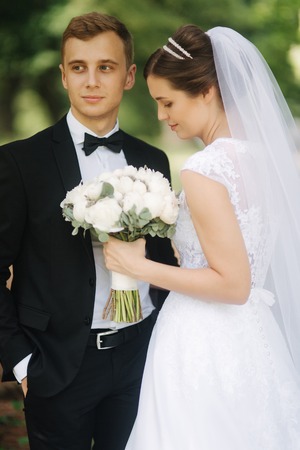 Newlyweds are walking in the park on the wedding day. Just married couple. Groom and bride on green backgroundの写真素材